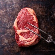 Raw fresh meat Ribeye Steak and meat fork on dark background